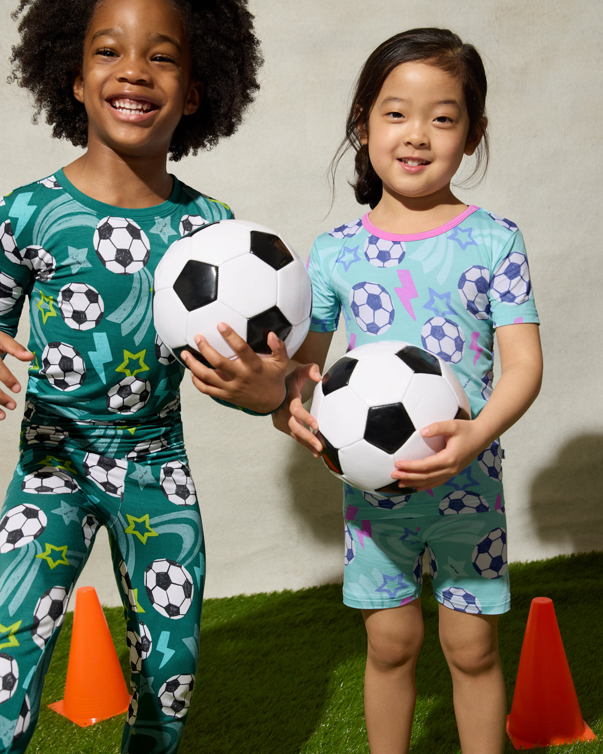 Two kids wearing matching Soccer Stars Two-Piece Pajama Sets playing with soccer balls