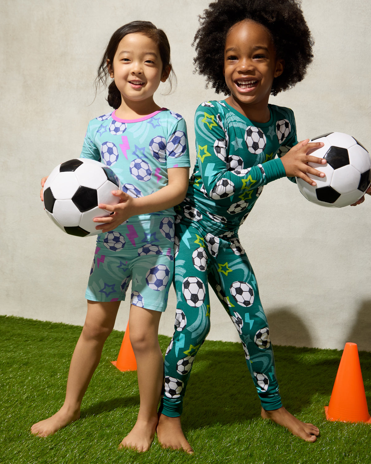 Two kids wearing matching Aqua and Green Soccer Stars Two-Piece Pajama Sets