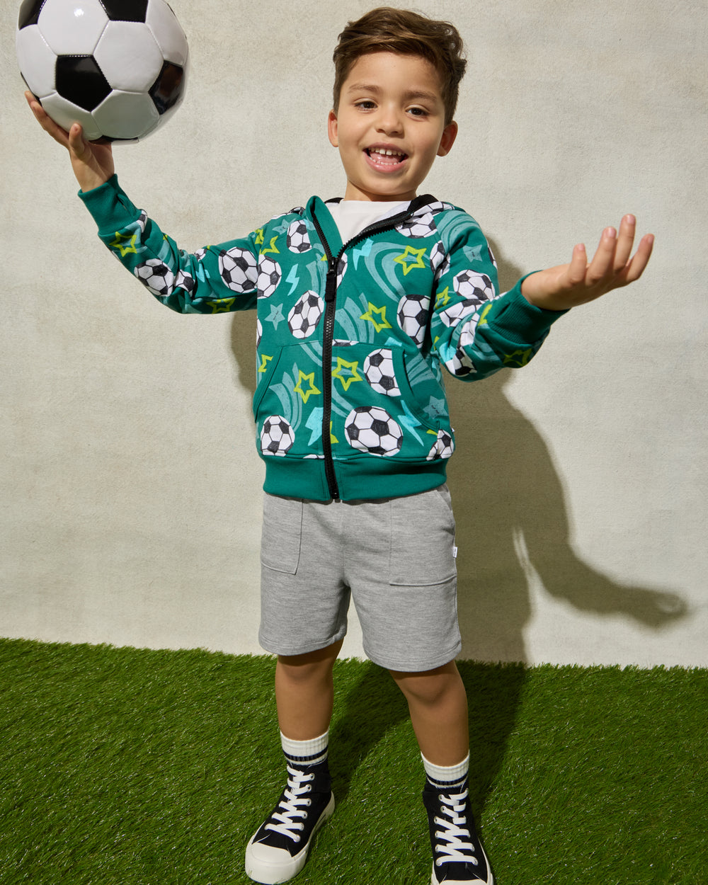 Boy wearing the Soccer Stars Zip Hoodie playing with a soccer ball