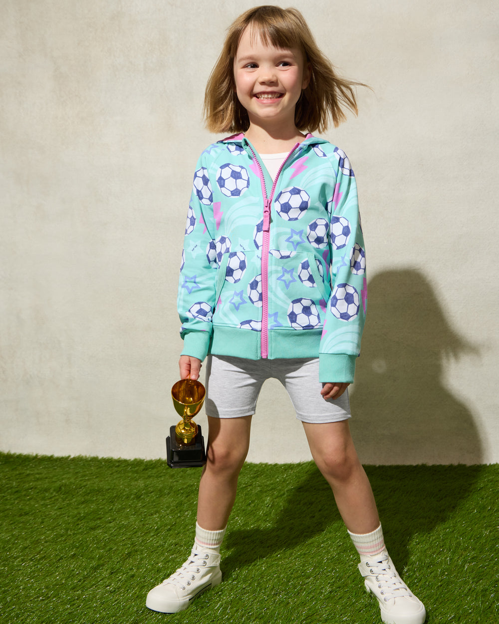 Girl wearing the Aqua Soccer Stars Zip Hoodie holding a trophy