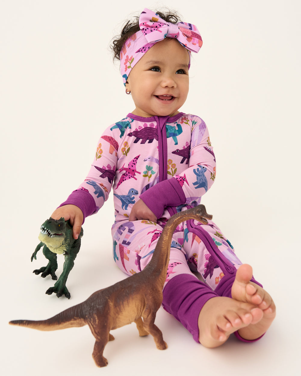 Baby wearing the Pink Roar & Explore Zippy playing with dinosaur toys
