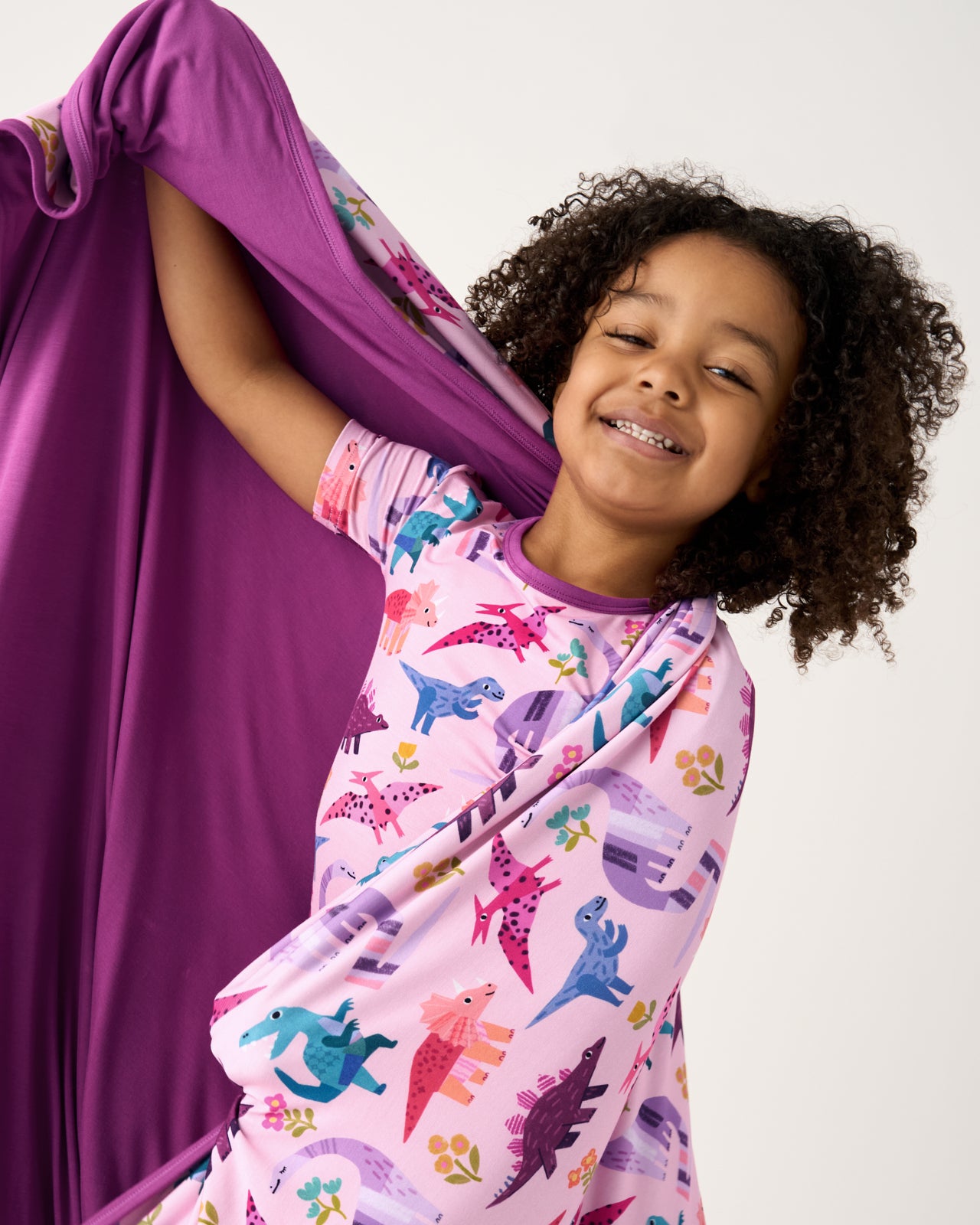 Girl showing the solid purple side of the Pink Roar & Explore Large Cloud Blanket®