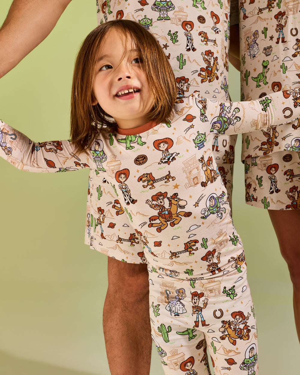 Girl wearing the Disney & Pixar Woody's Wild West Two-Piece Pajama Set on a green backdrop