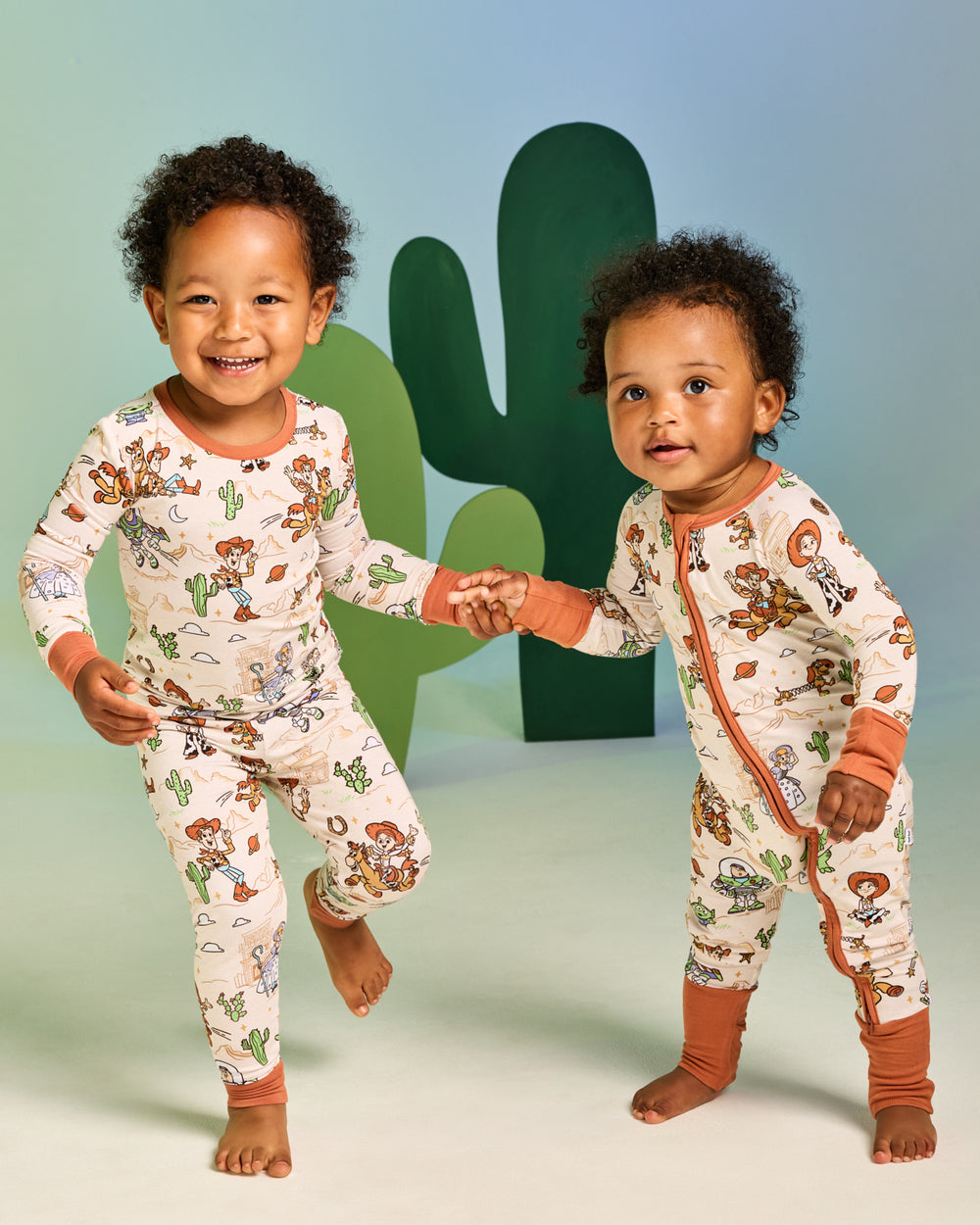 Two children wearing matching Disney & Pixar Woody's Wild West pajamas
