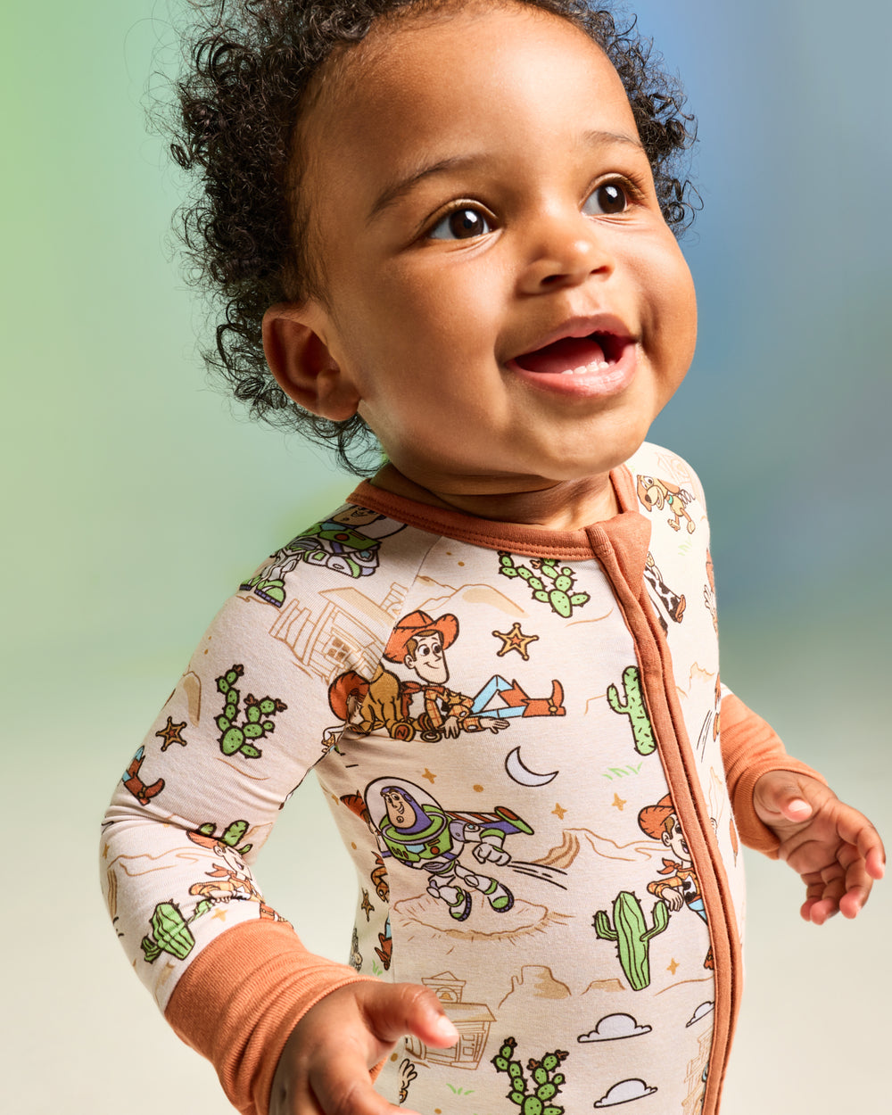Close up of baby wearing the Disney & Pixar Woody's Wild West Zippy on a green background
