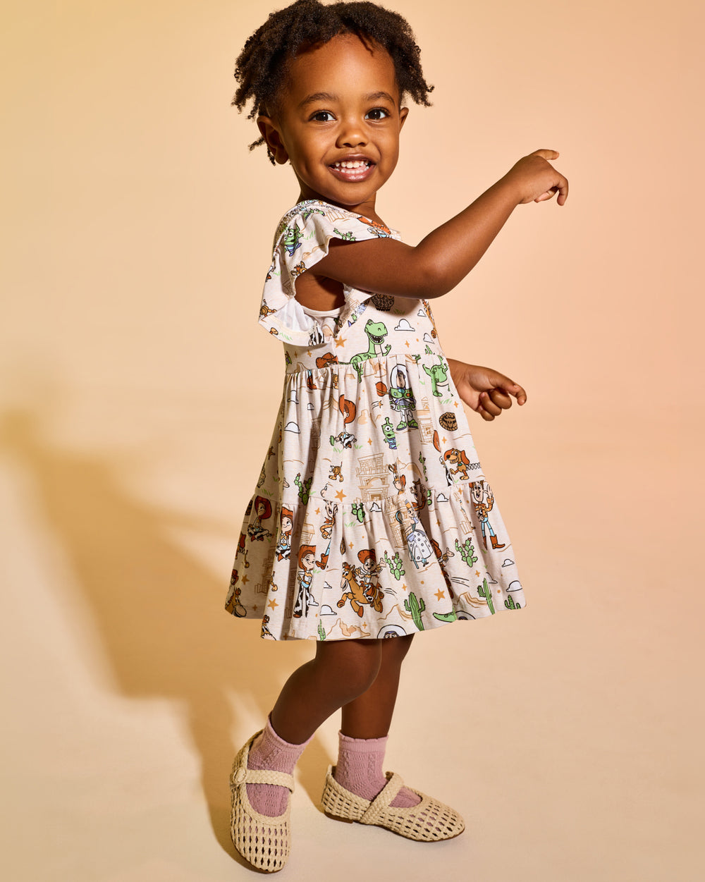Girl wearing the Disney & Pixar Woody's Wild West Tiered Flutter Dress with Bloomer with woven mary janes 