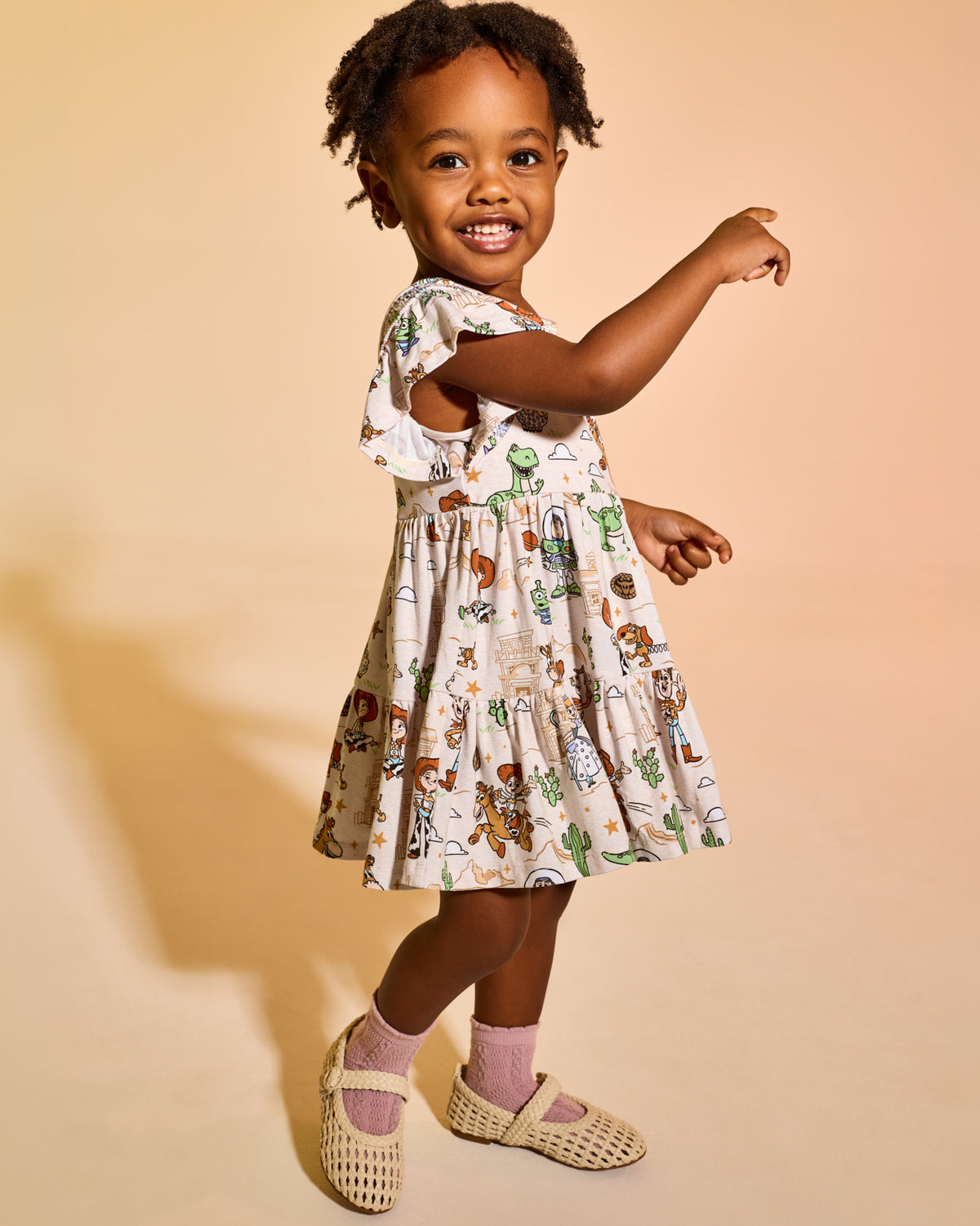 Girl wearing the Disney & Pixar Woody's Wild West Tiered Flutter Dress with Bloomer with woven mary janes 