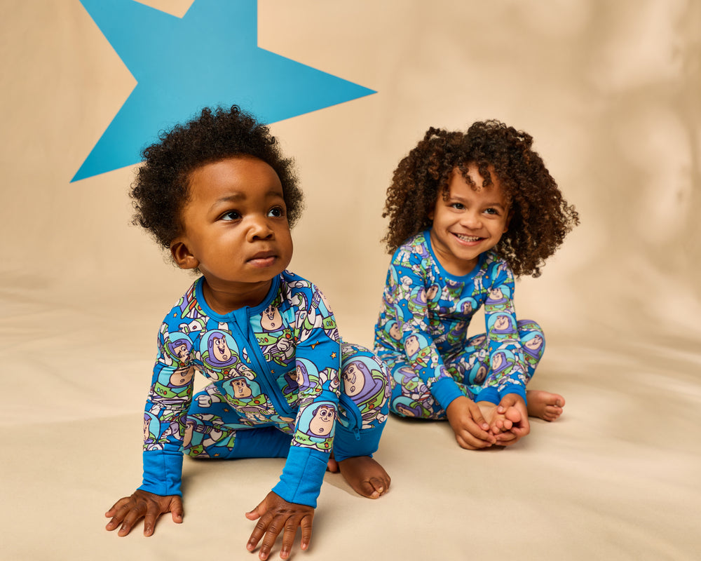 Two children wearing matching Disney & Pixar Buzz's Cosmic Crew pajamas