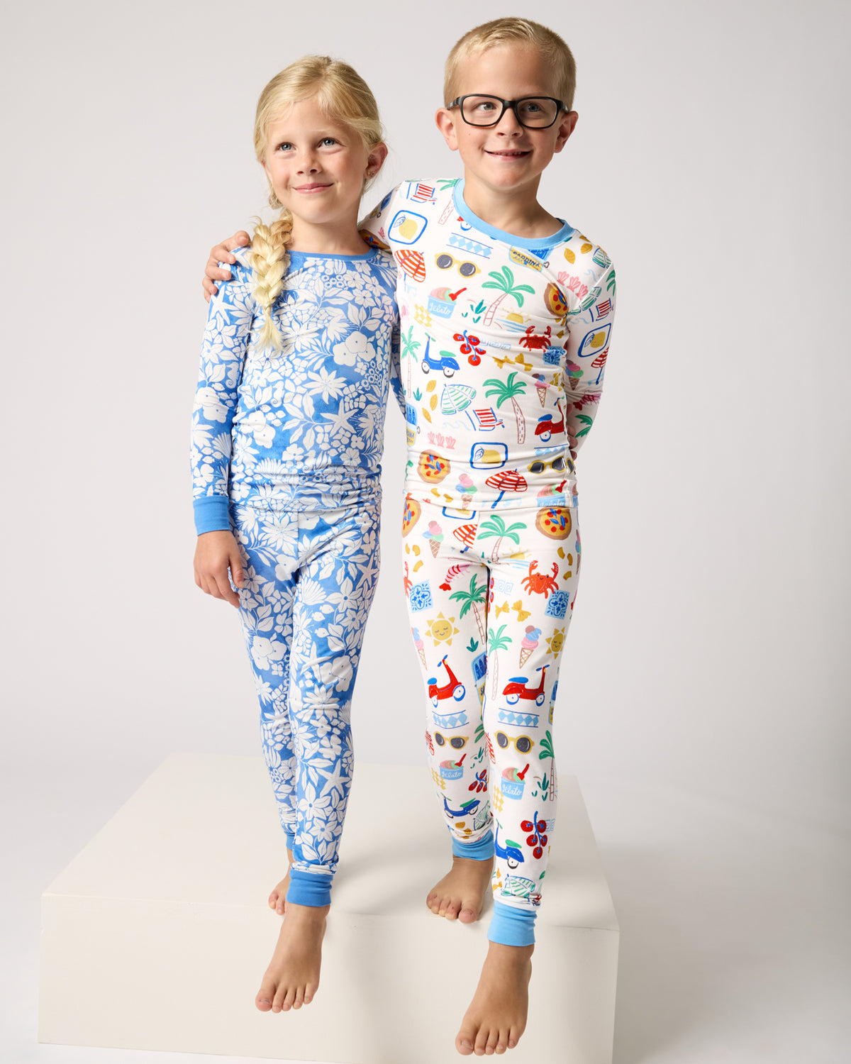 Two children wearing Azure Garden and Ciao Bella Two-Piece Pajama Sets
