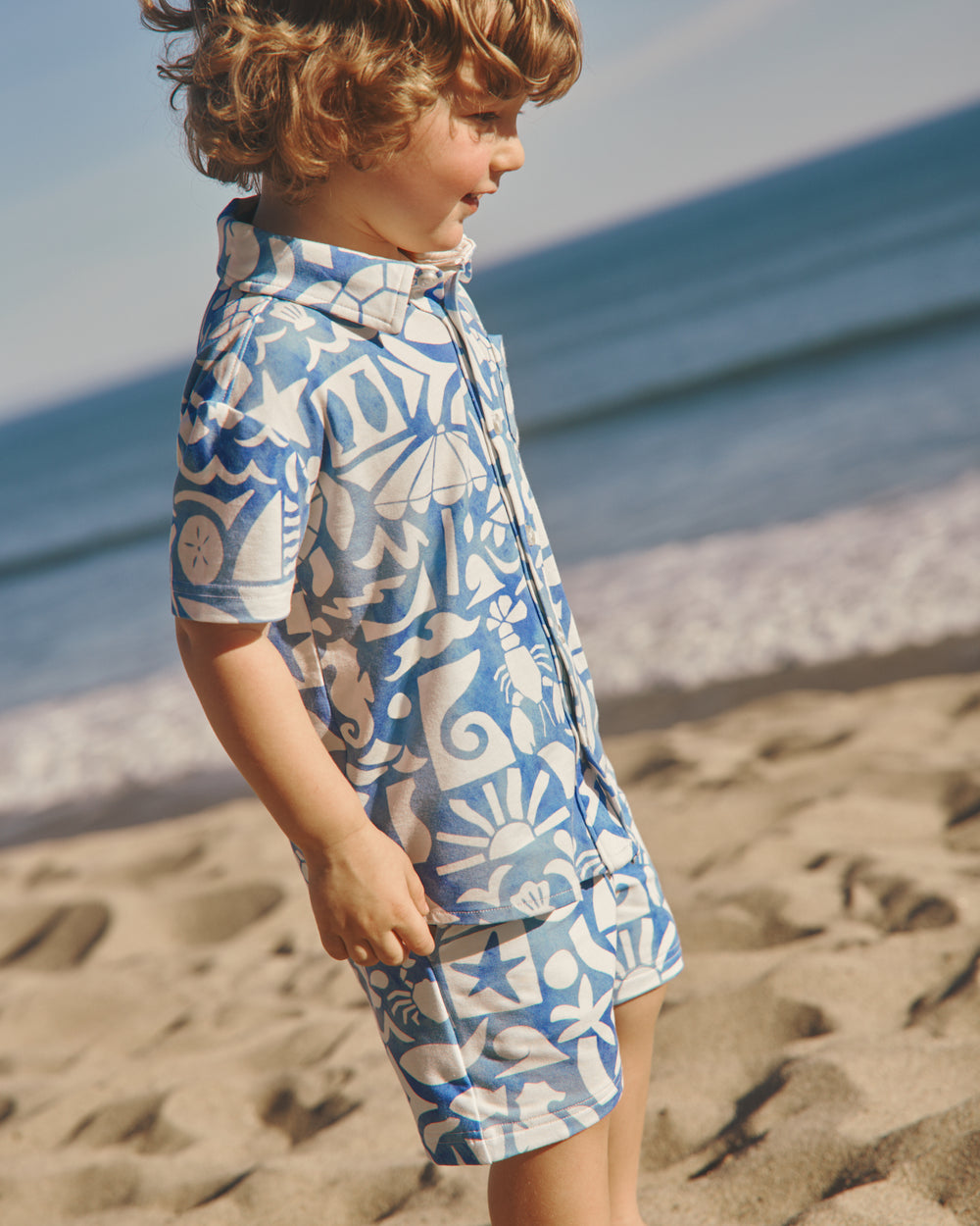 Boy wearing the Summer Shores Button Down Polo and Shorts on a beach