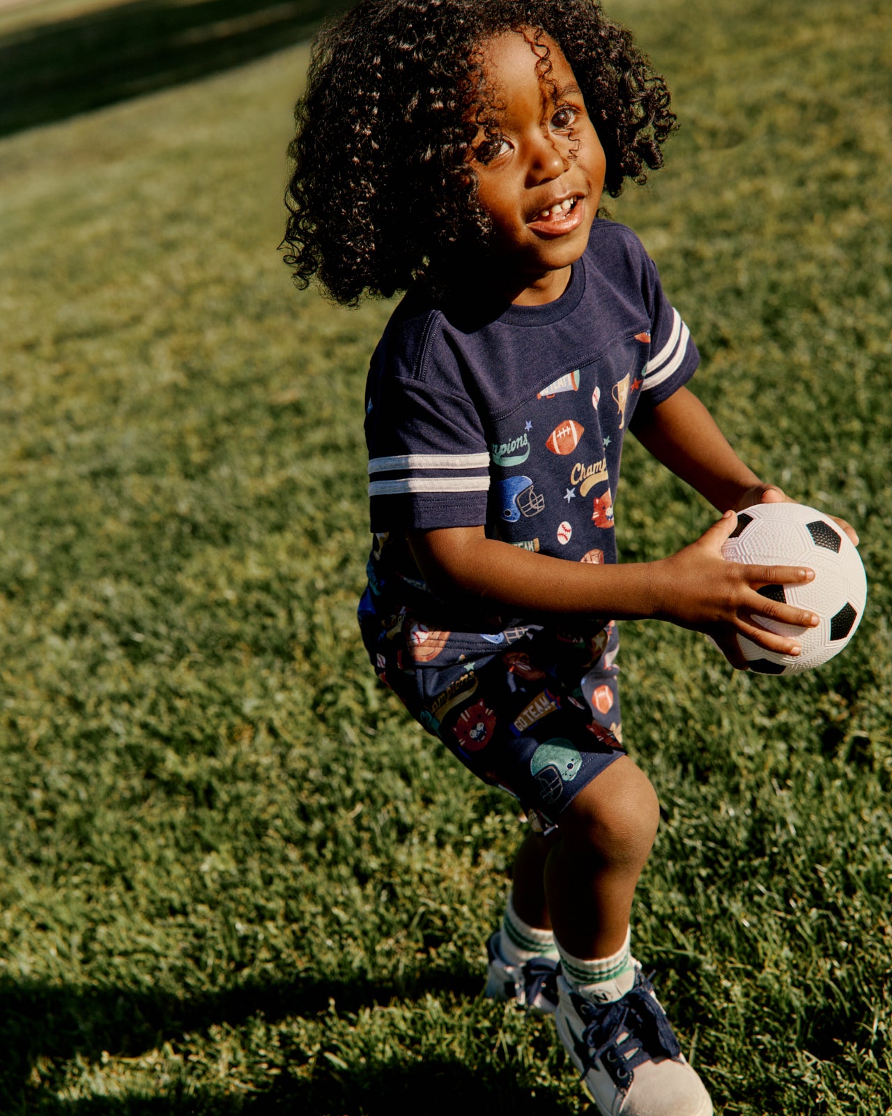 Boy wearing the Team Spirit Relaxed Tee and Shorts holding a soccer ball