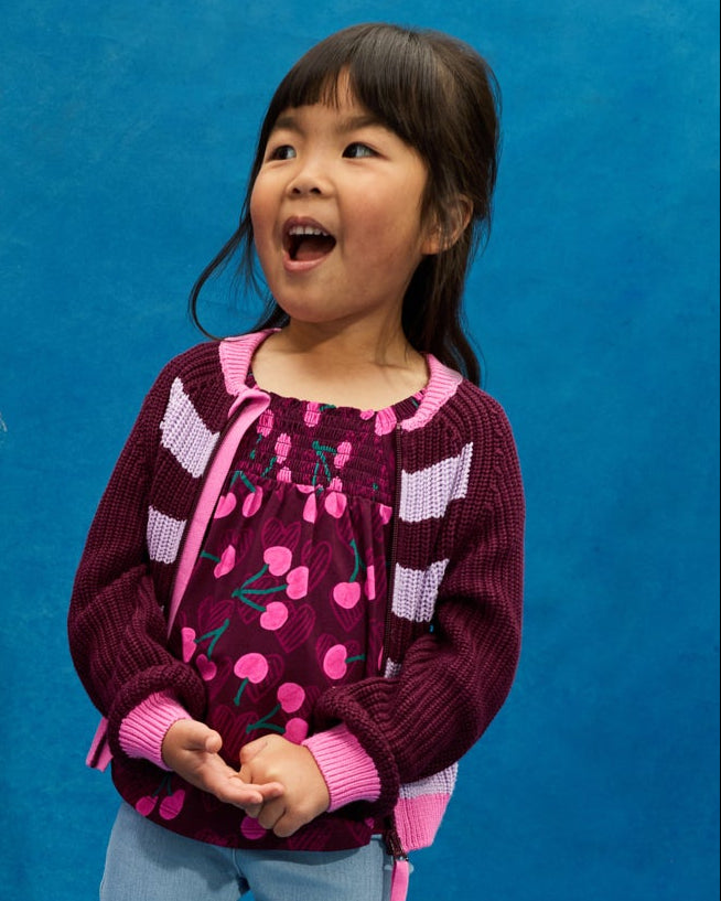 Girl wearing the Powder Lilac Stripe Bomber Jacket over a cherry print btop