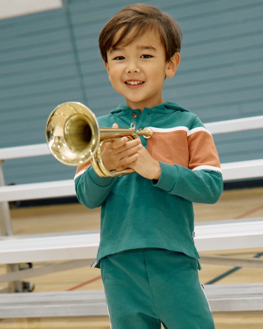 Boy wearing the Emerald Isle Henley Hoodie holding a trumpet