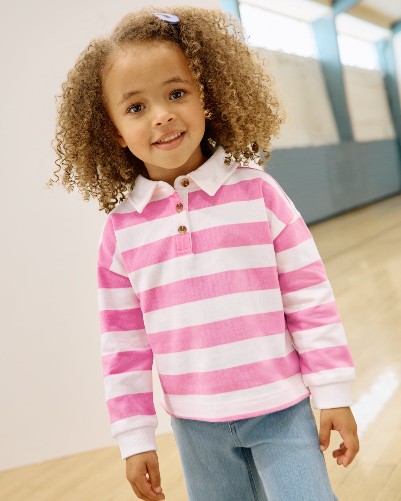 Girl wearing the Pink Spark Stripe Polo Shirt in a gymnasium