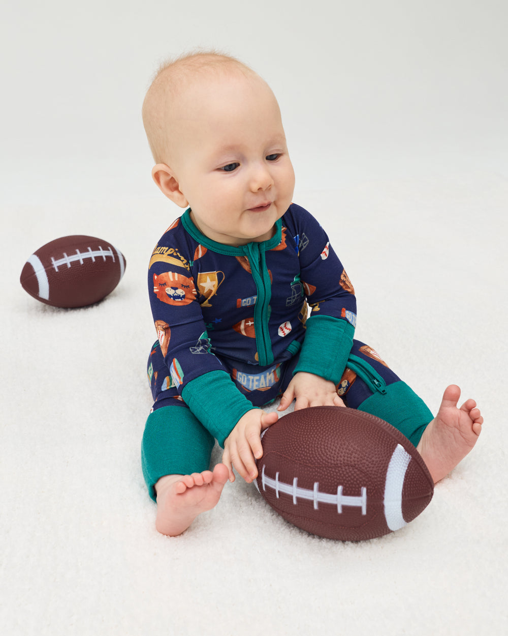 Baby wearing the Team Spirit Zippy playing with a football