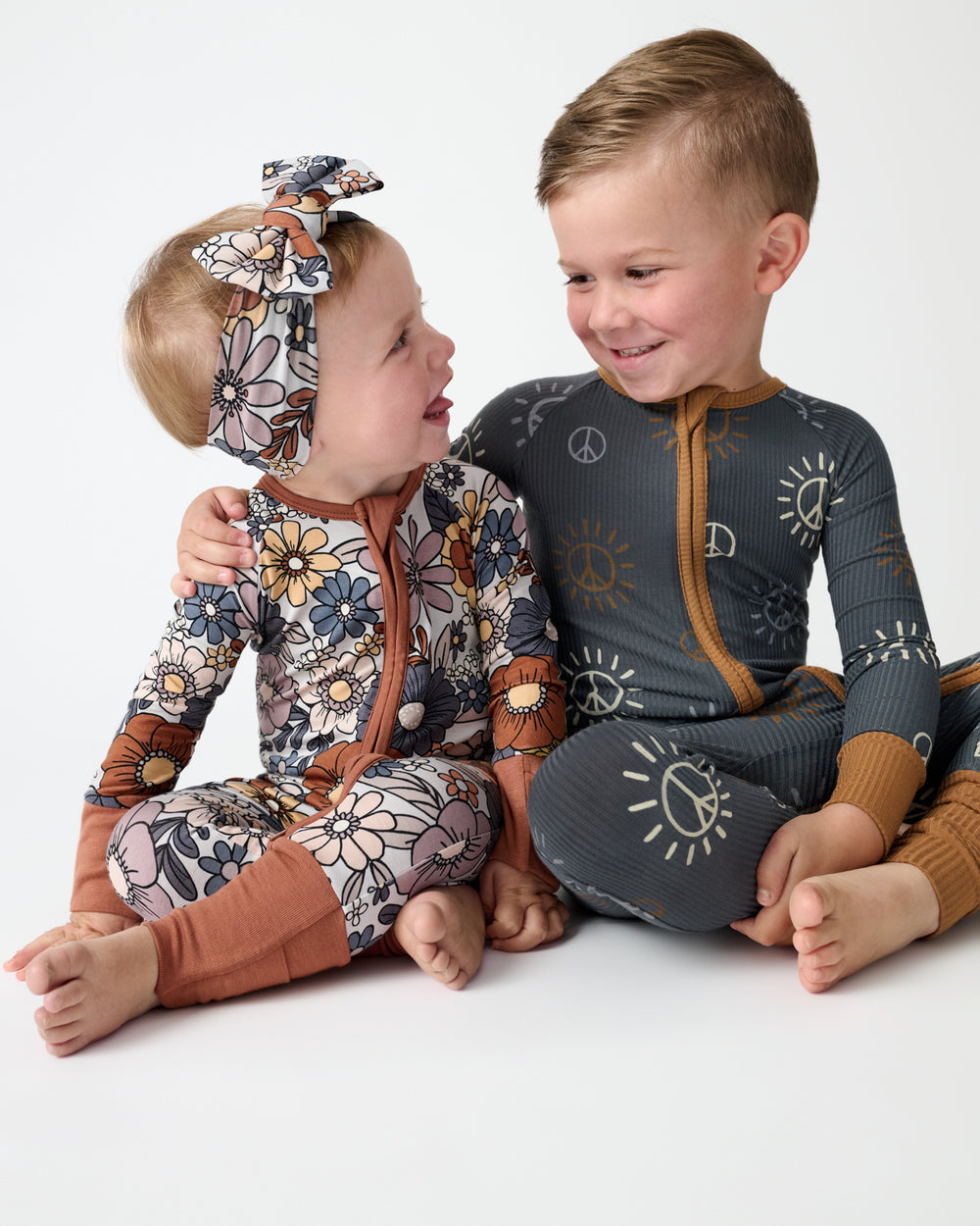 Two children wearing Wildwood Floral and Peace & Love Zippies