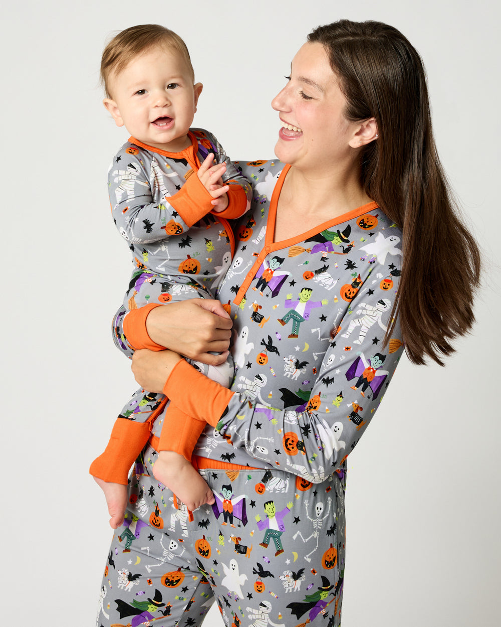 Woman wearing the Dracula's Disco Women's Long Sleeve Pajama Top holding a baby in matching halloween PJs