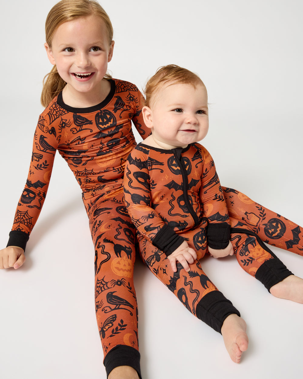 Two siblings wearing matching Midnight Mischief Halloween Pajamas