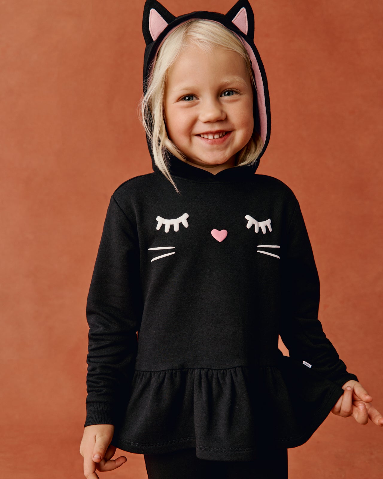 Girl wearing the Black Cat Peplum Hoodie on an orange back drop