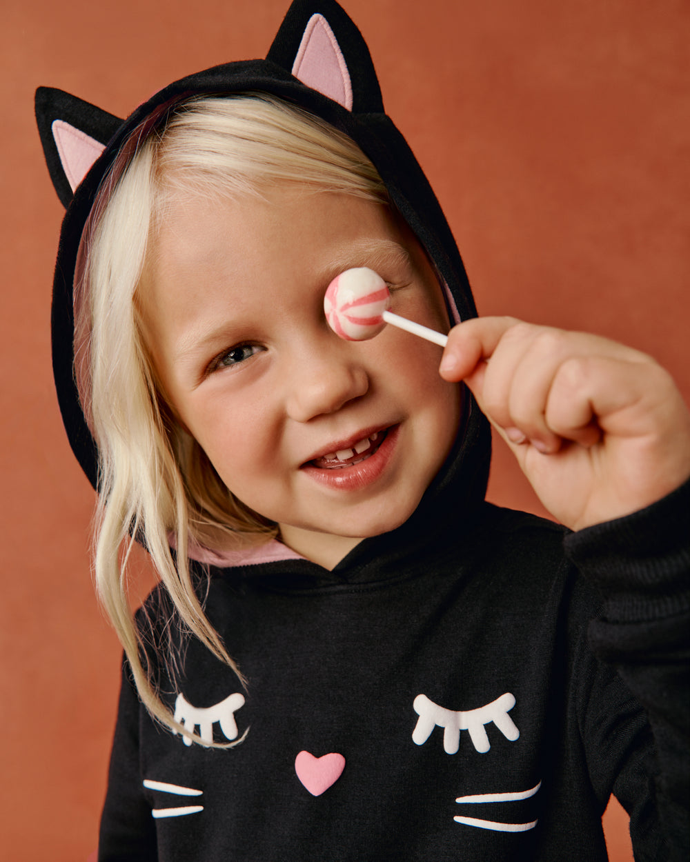 Girl wearing the Black Cat Peplum Hoodie holding a lollipop  