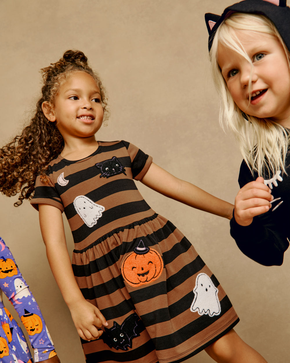 Girl wearing the Spooky Stripes Dress on a brown back drop