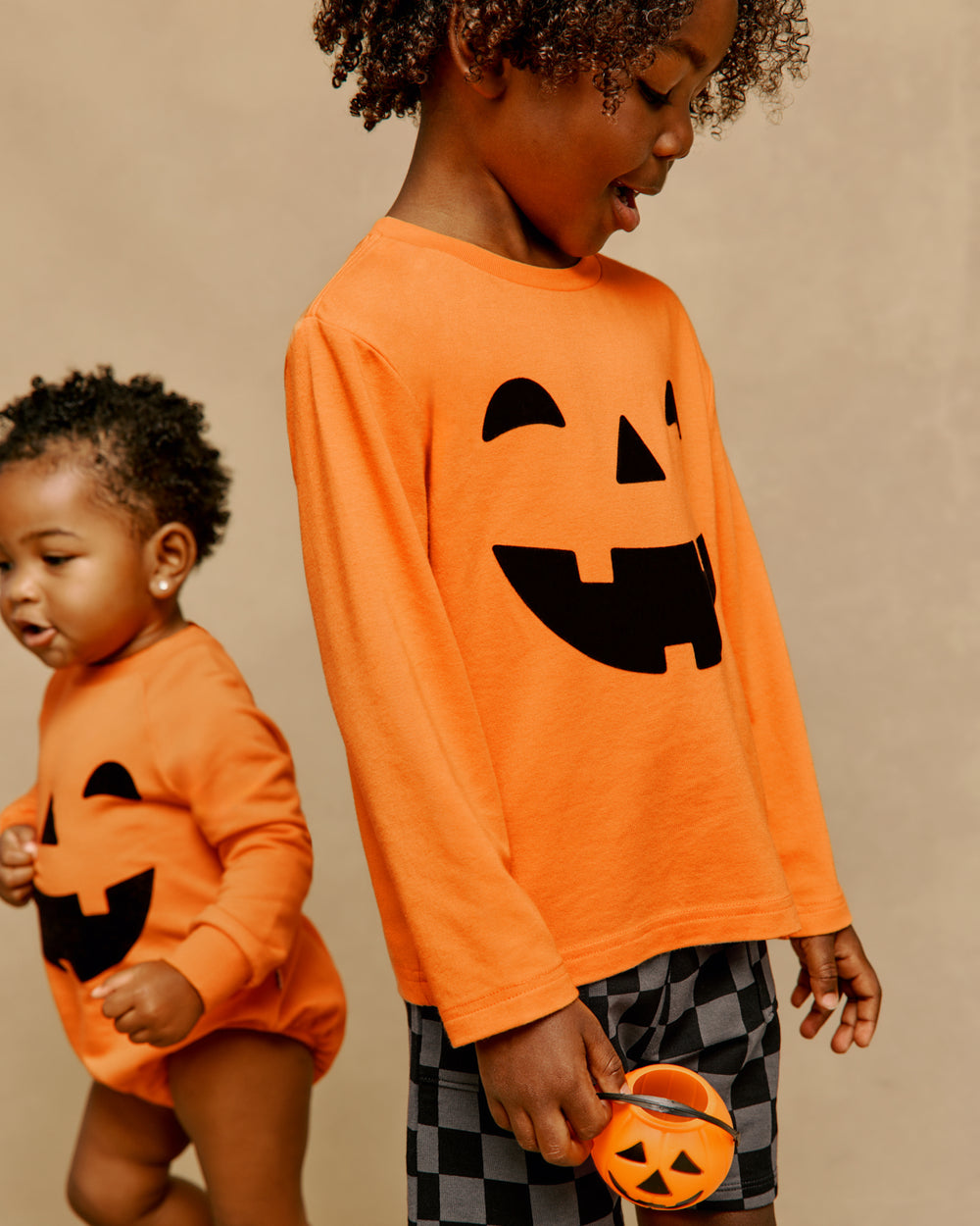 Two children wearing Jack-O'-Lantern Halloween styles