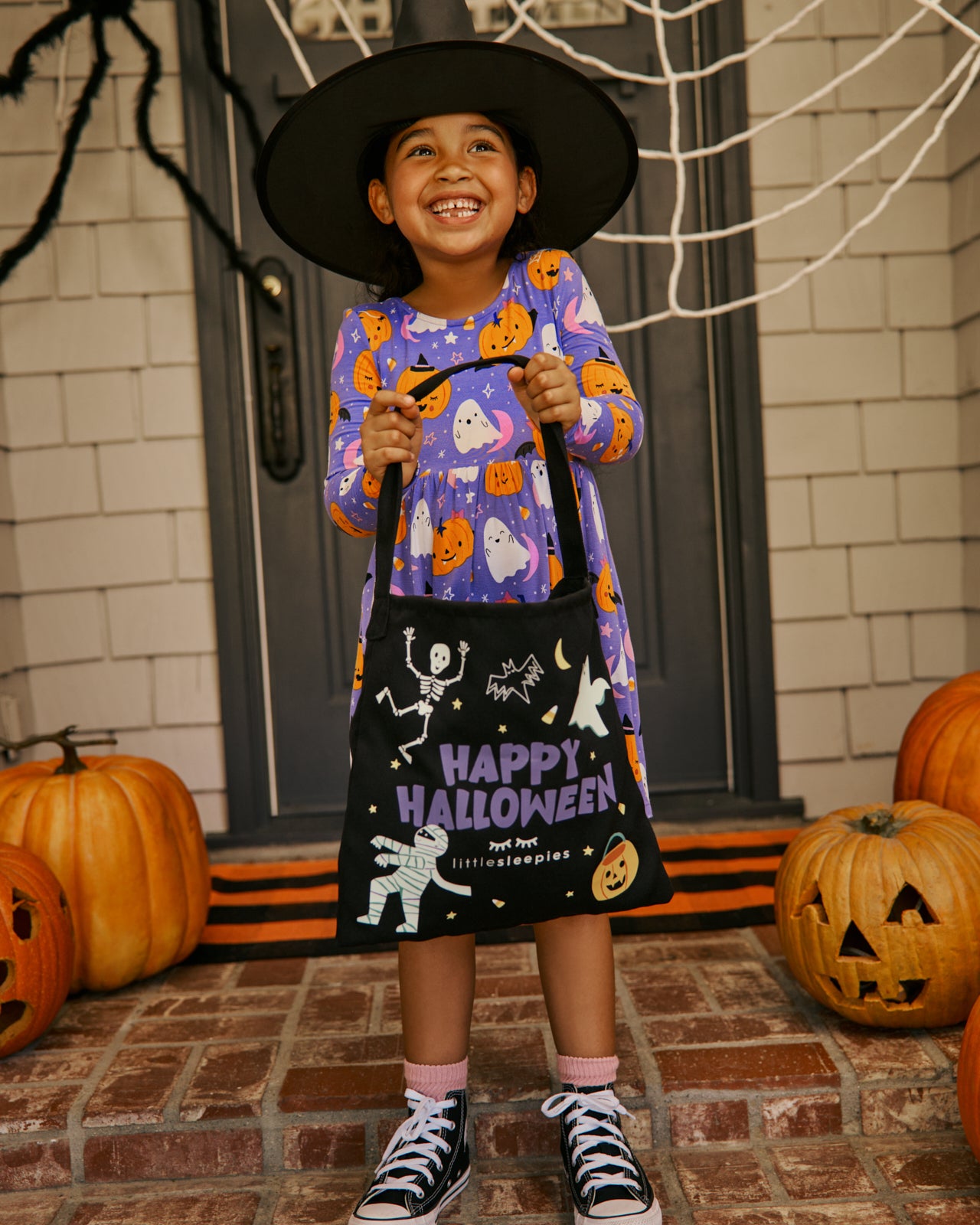 Girl holding the Little Sleepies Halloween Treat Bag wearing a halloween dress