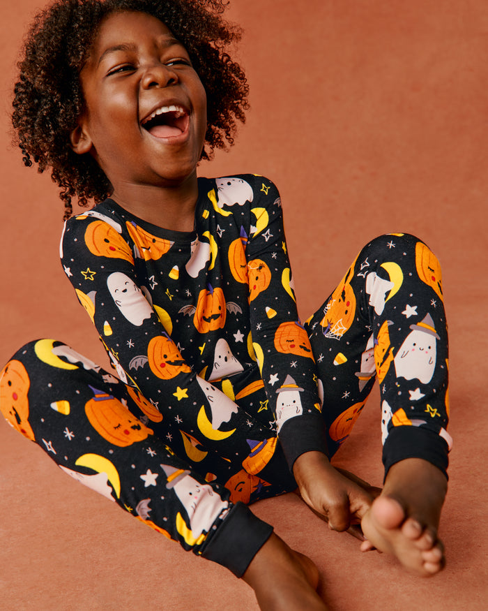 Boy wearing the Moonlit Magic Two-Piece Pajama Set on an orange back drop