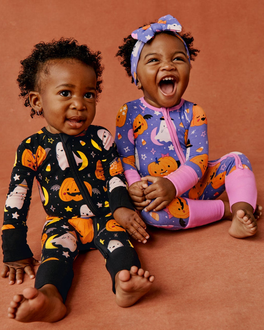 Two babies wearing matching Glow in the Dark Halloween print footie pajamas