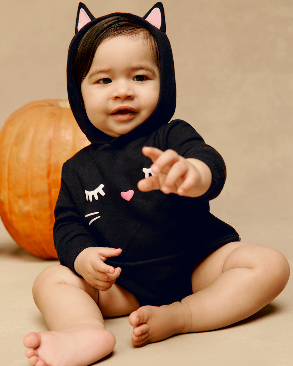 Baby wearing the Black Cat Hoodie Romper on a tan back drop