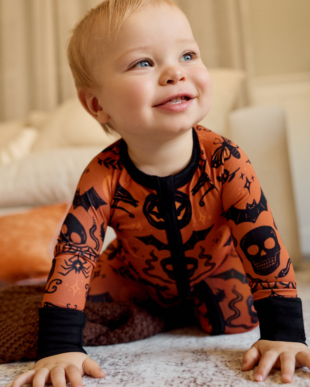 Crawling baby wearing the Midnight Mischief Zippy in a living room