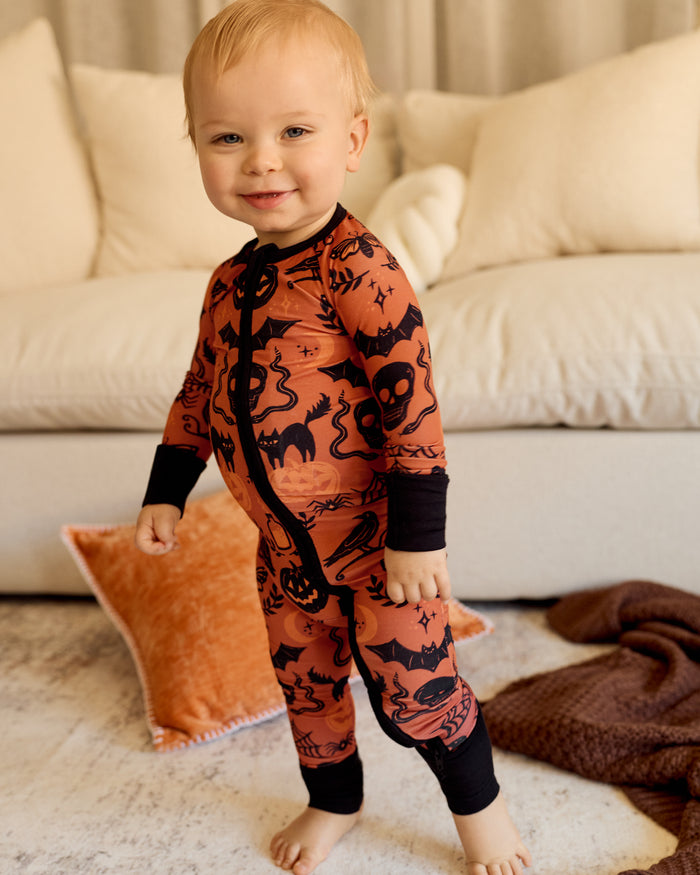 Standing baby wearing the Midnight Mischief Zippy in a living room