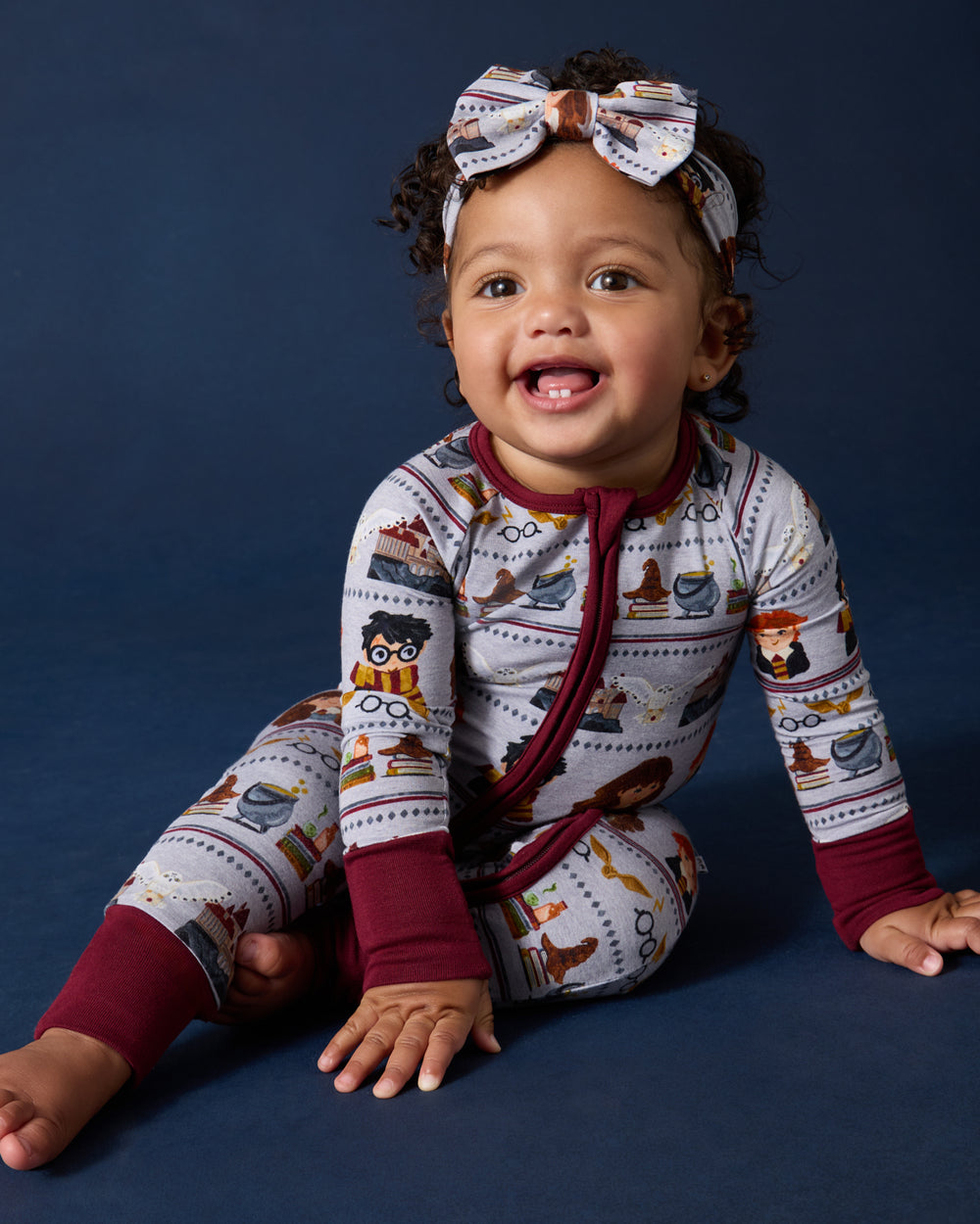 Baby girl wearing the Harry Potter™ Spellbinding Studies Zippy with a Luxe Bow Headband