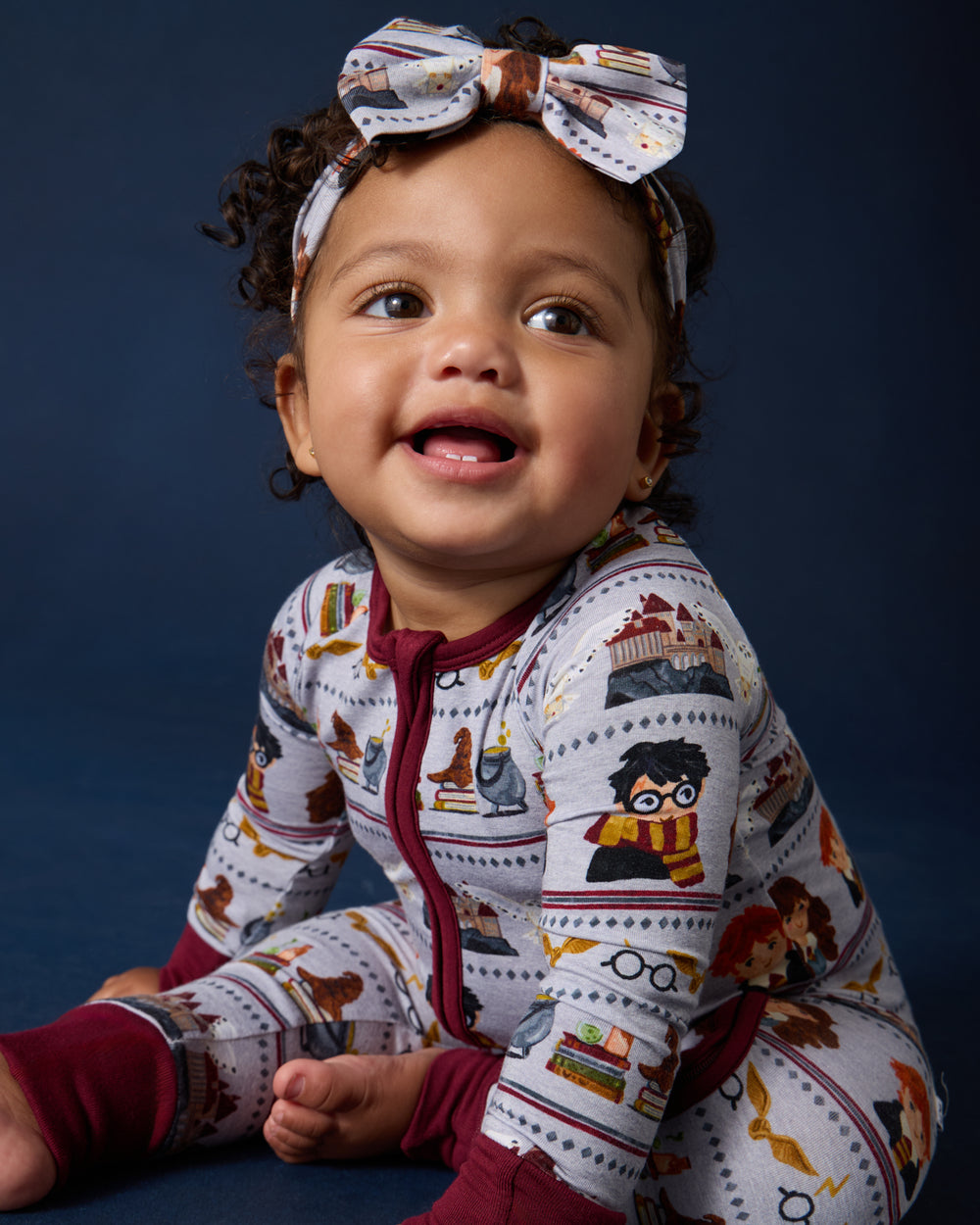 Baby wearing the Harry Potter™ Spellbinding Studies Luxe Bow Headband with a matching footie PJ