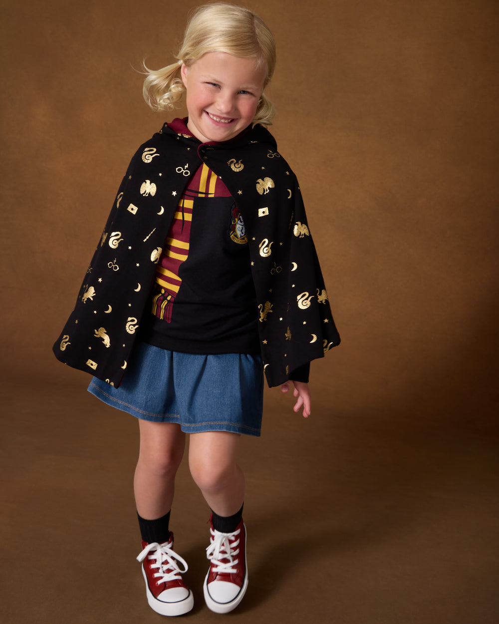 Girl wearing the Harry Potter™ Spellbinding Studies Hooded Cloak over a Gryffindor crewneck