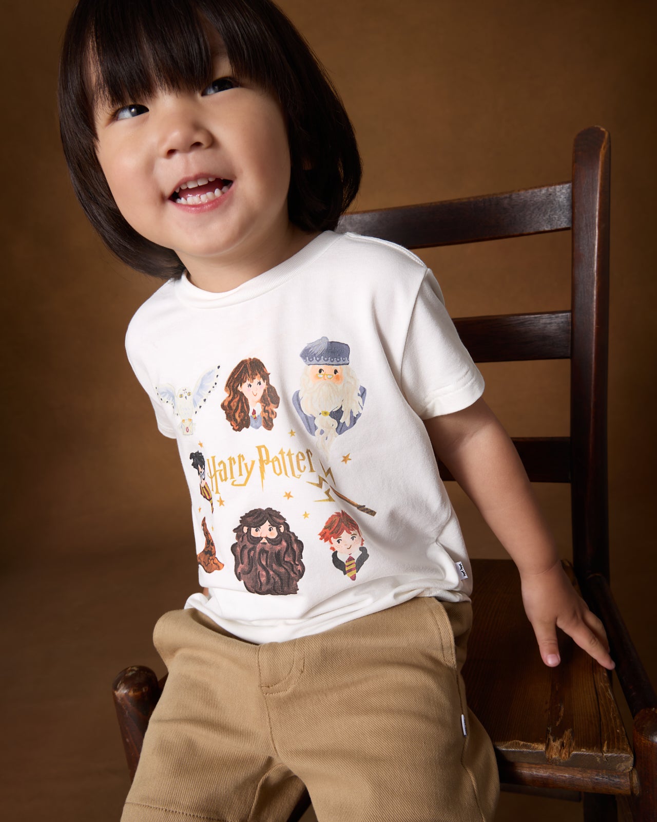 Child wearing the Harry Potter™ Spellbinding Studies Relaxed Tee on a brown back drop