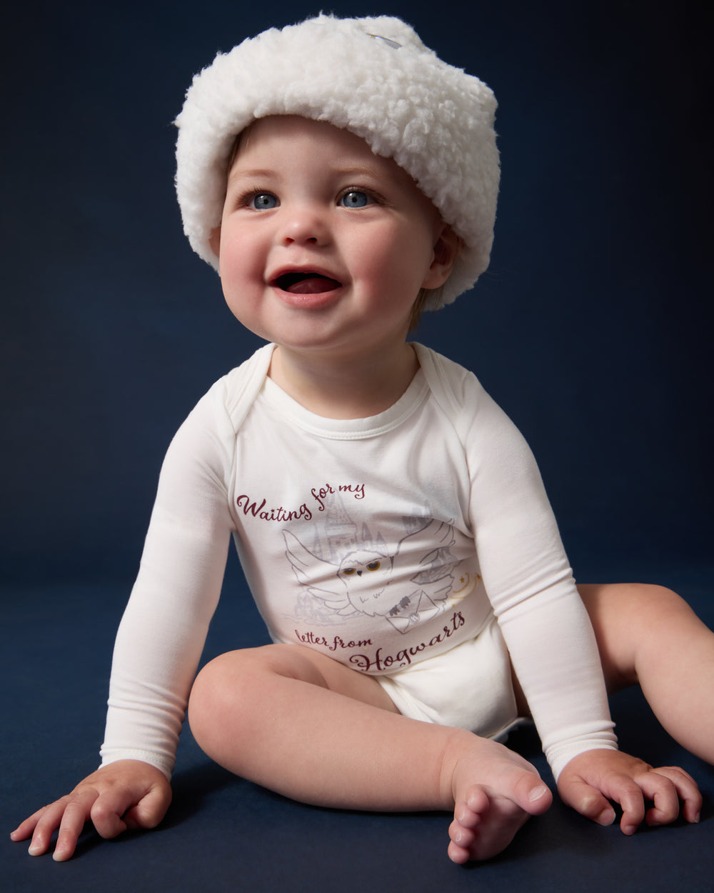 Sitting newborn wearing the Harry Potter™ Hedwig Bodysuit and Beanie