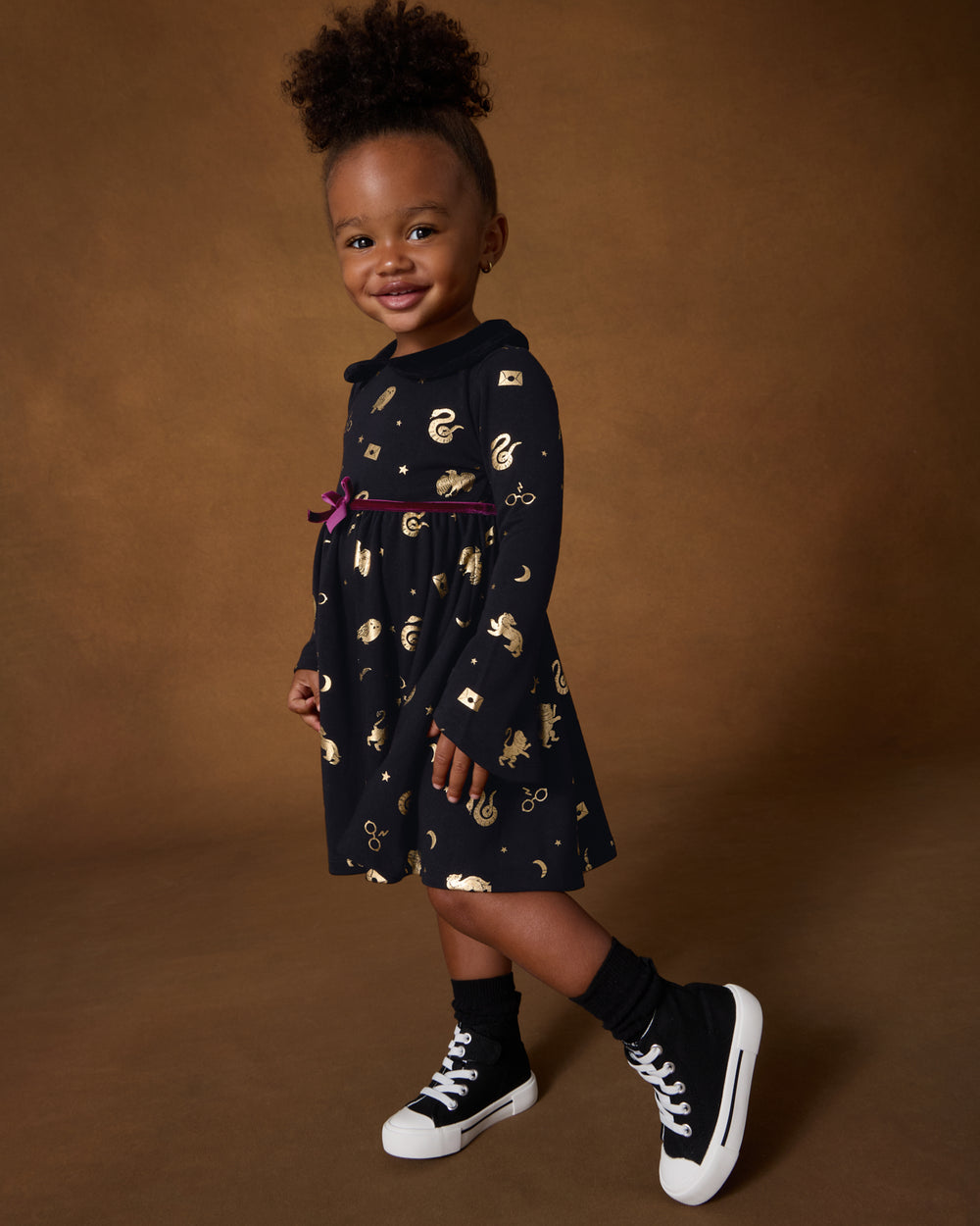 Girl wearing the Harry Potter™ Spellbinding Studies Flare Sleeve Twirl Dress on a brown back drop