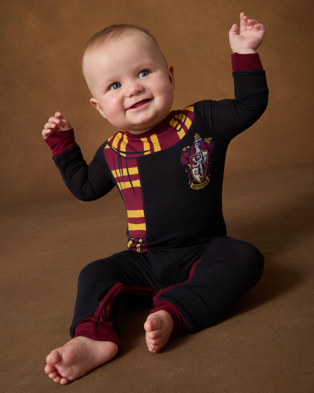 Baby wearing the Harry Potter™ Gryffindor Crescent Zippy on a brown backdrdop