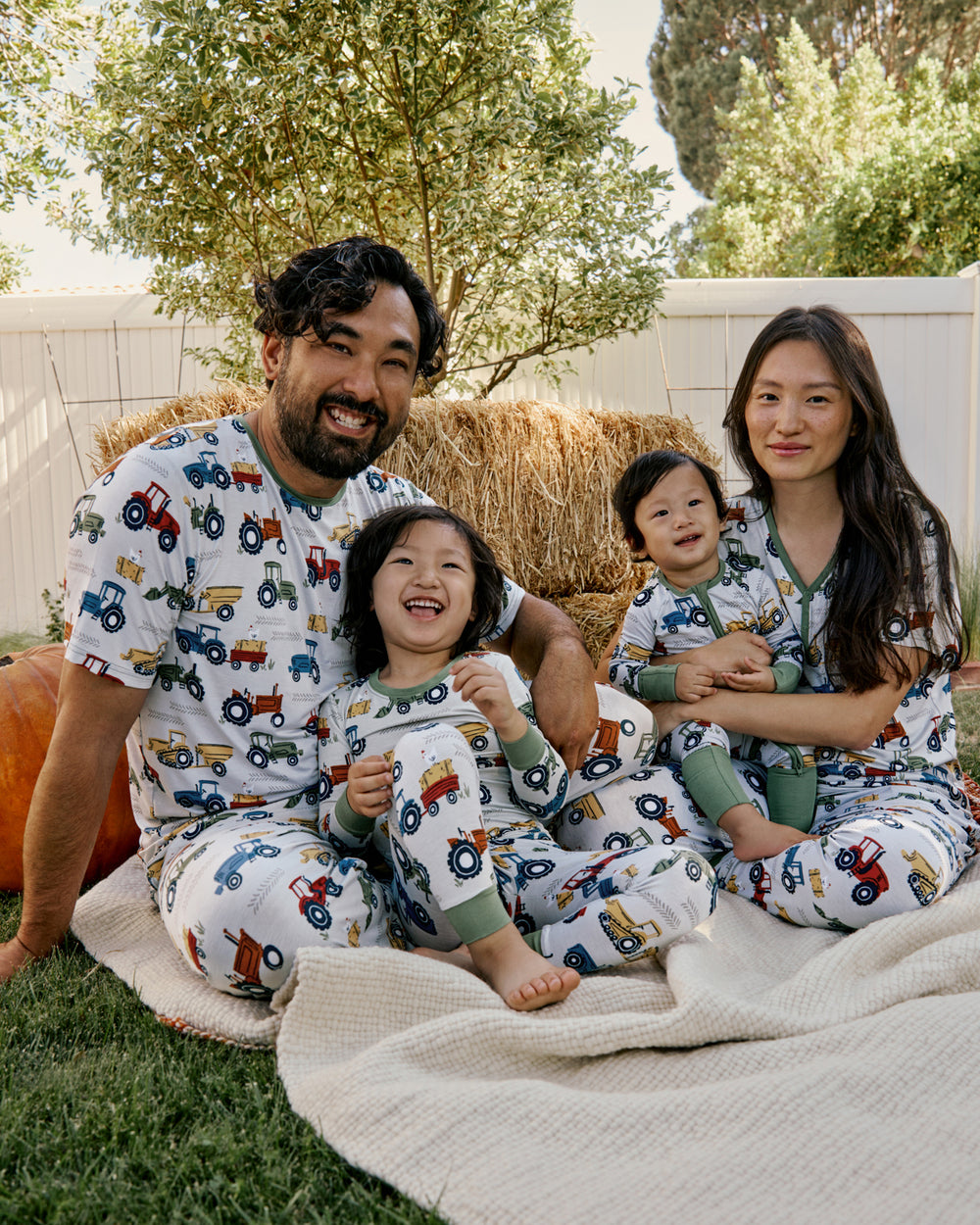 Family of four wearing the Tractor Tales Men's Short Sleeve Pajama Top with a Fall themed back drop