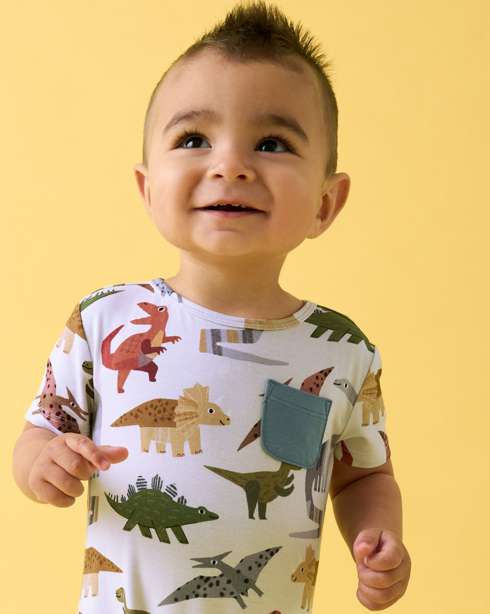 Close up of boy wearing the Roar & Explore Pocket Shorty Romper on a yellow backdrop