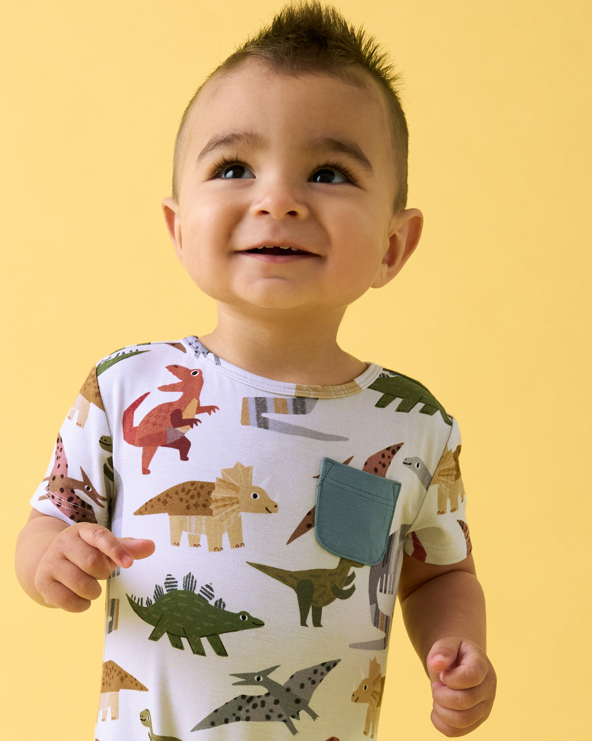 Close up of boy wearing the Roar & Explore Pocket Shorty Romper on a yellow backdrop
