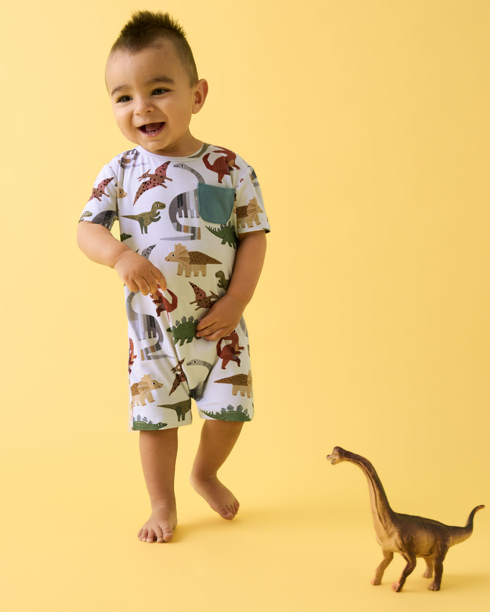 Boy wearing the Roar & Explore Pocket Shorty Romper on a yellow background