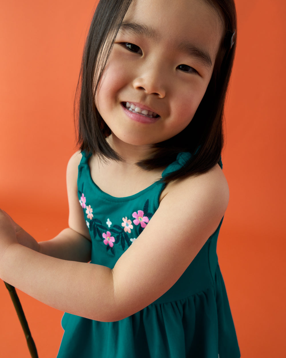 Girl wearing the Midnight Tide Embroidered Peplum Tank on an orange back drop