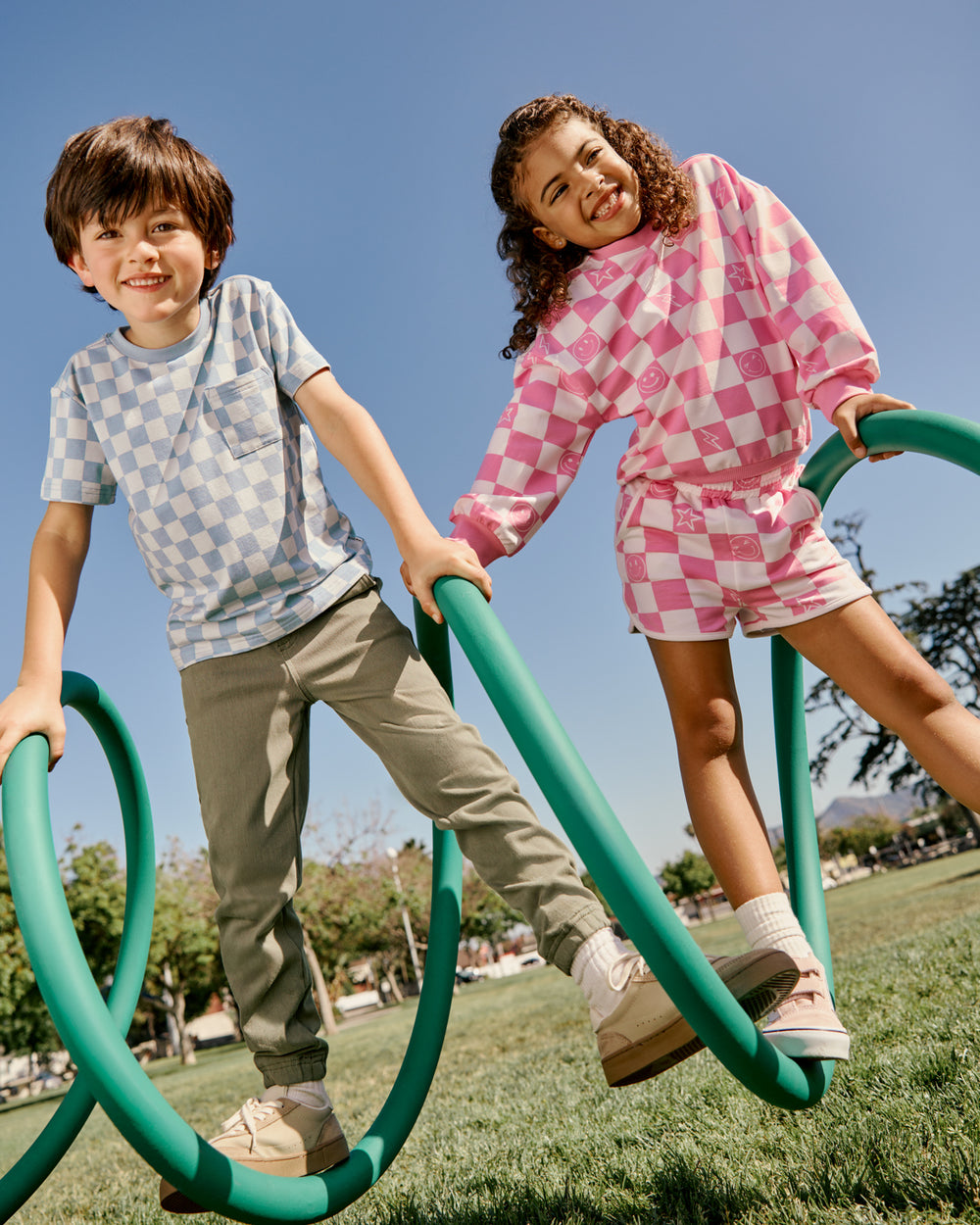 Two kids wearing checkered clothing on a playground