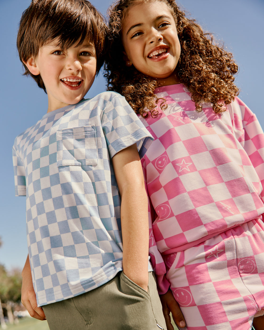 Boy and girl wearing Checkered tops with a blue back drop