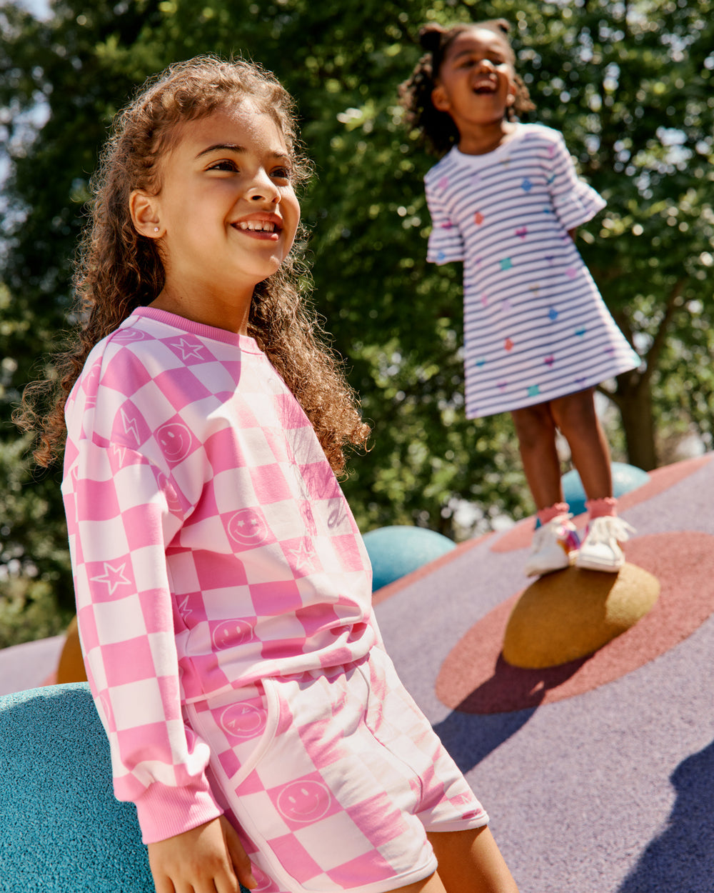 Girl wearing the Cheery Checks Pink Drop Shoulder Sweatshirt and Shorts on a playscape