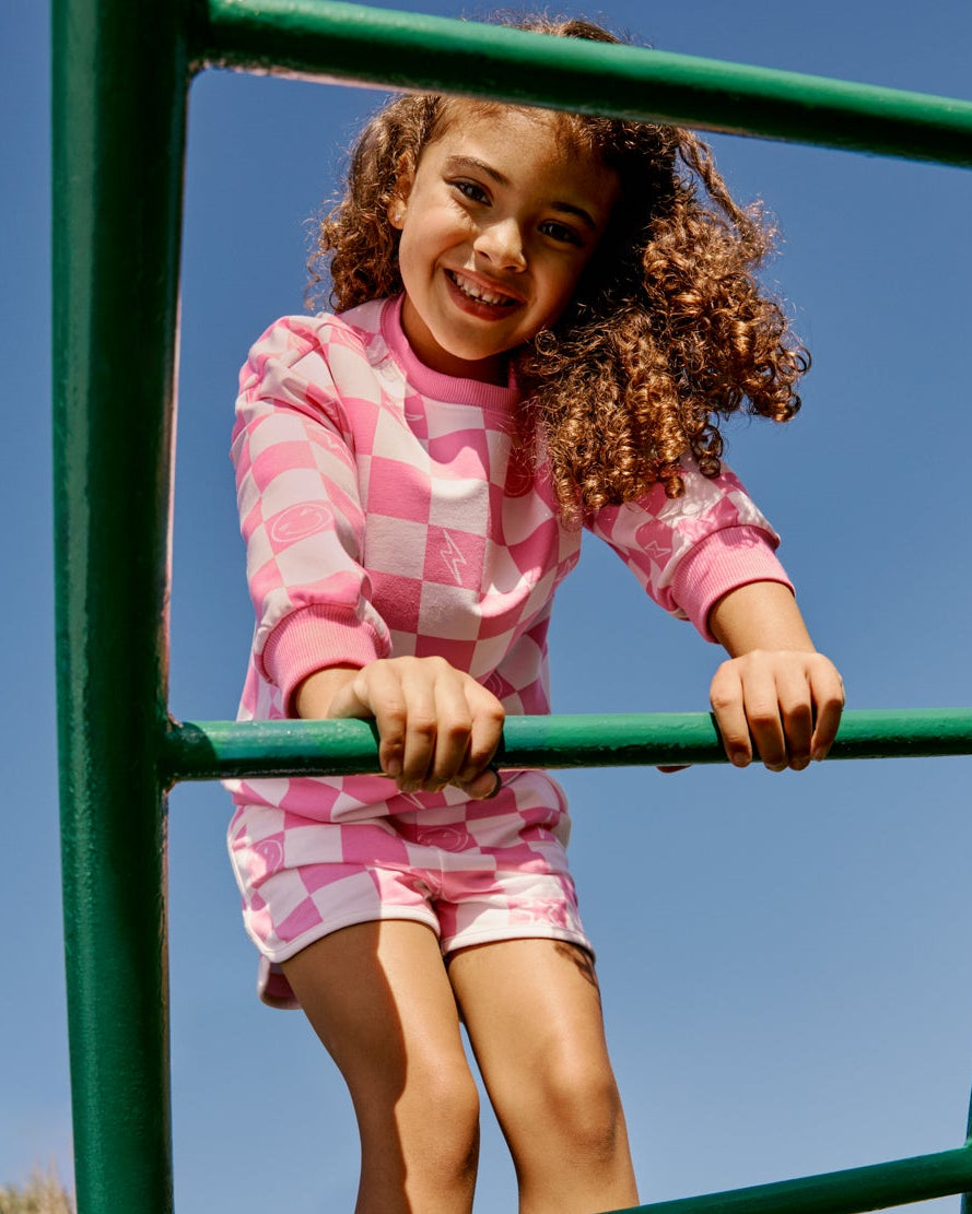 Girl wearing the Cheery Checks Pink Dolphin Shorts on a playground