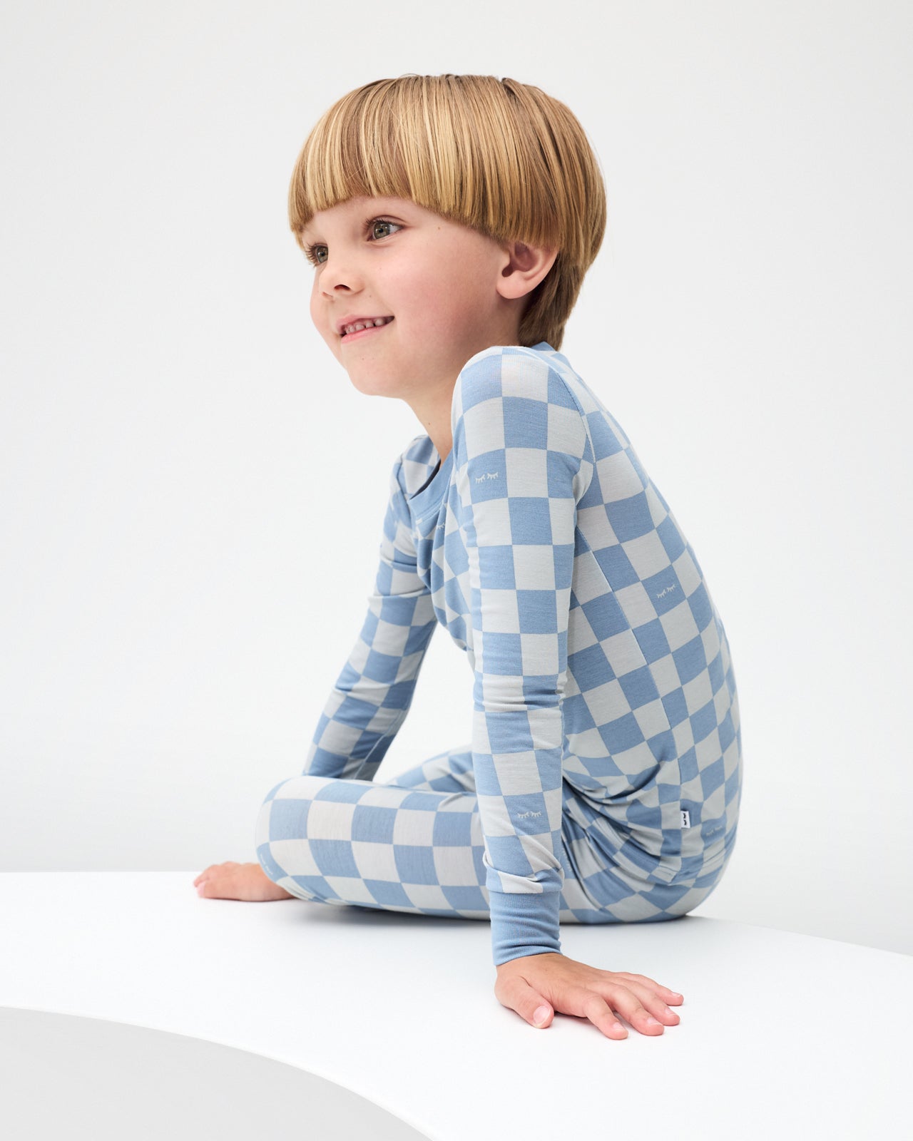 Sitting boy wearing the Dusk Blue Checks Two-Piece Pajama Set