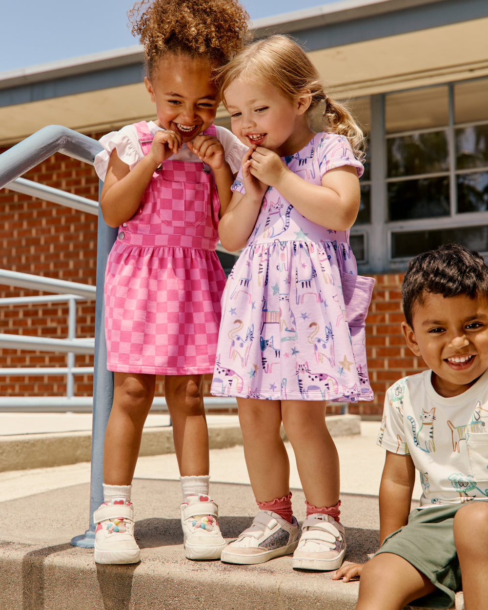 Two girls wearing back to school dresses in front of a school